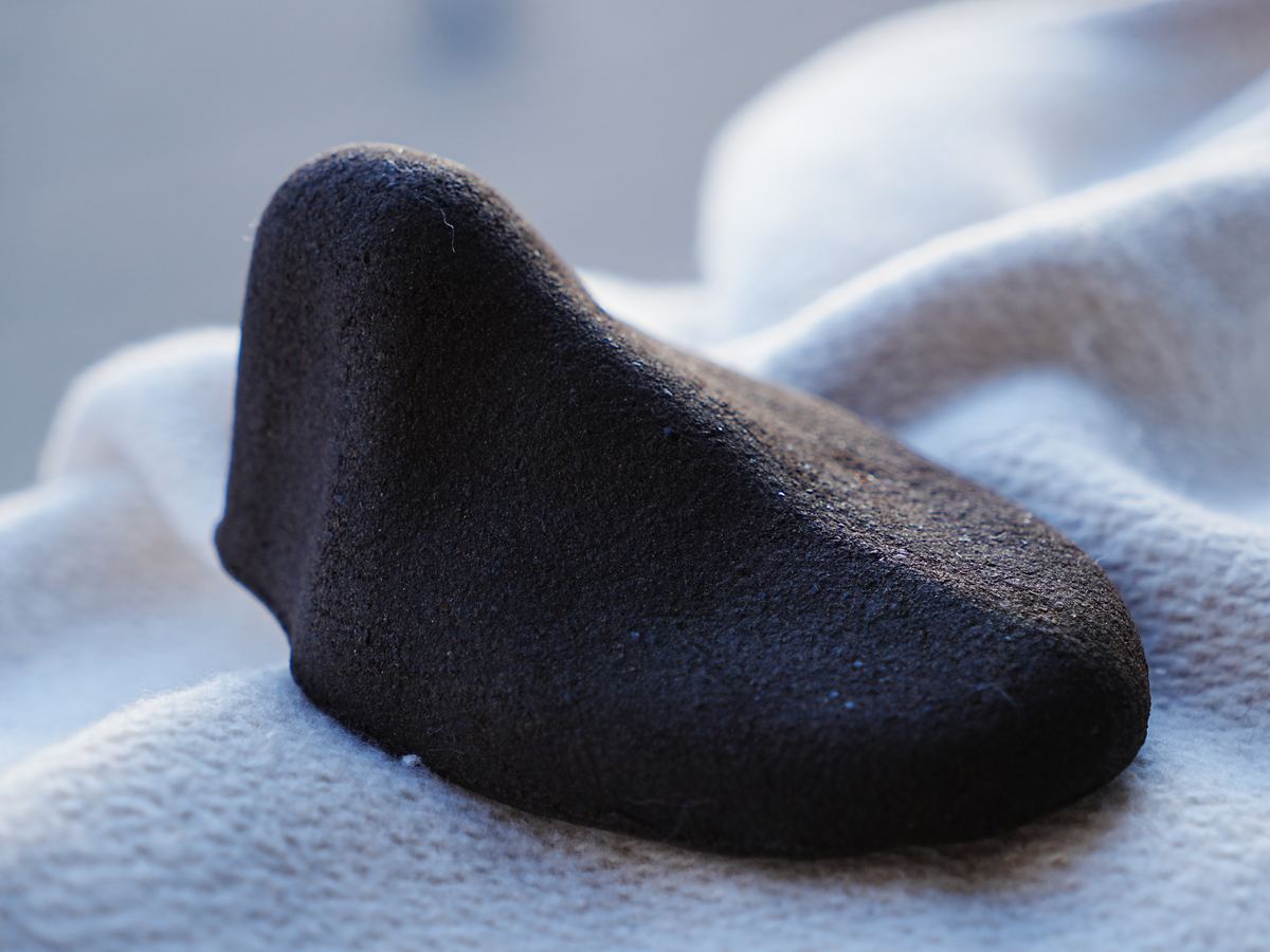 Dark Kahyve shoe tree resting on linen in soft daylight